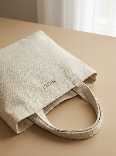 Tote de pilates en toile écrue sur fond sable, lumière naturelle douce