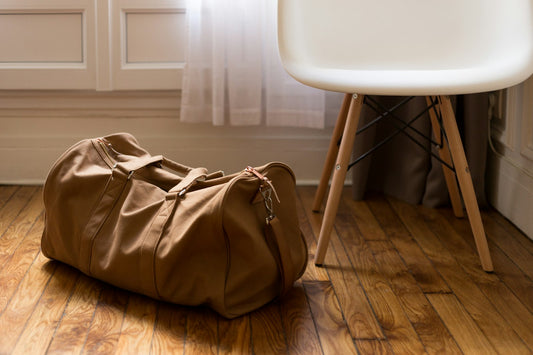 Grand sac duffel de sport en toile sable posé sur un parquet clair