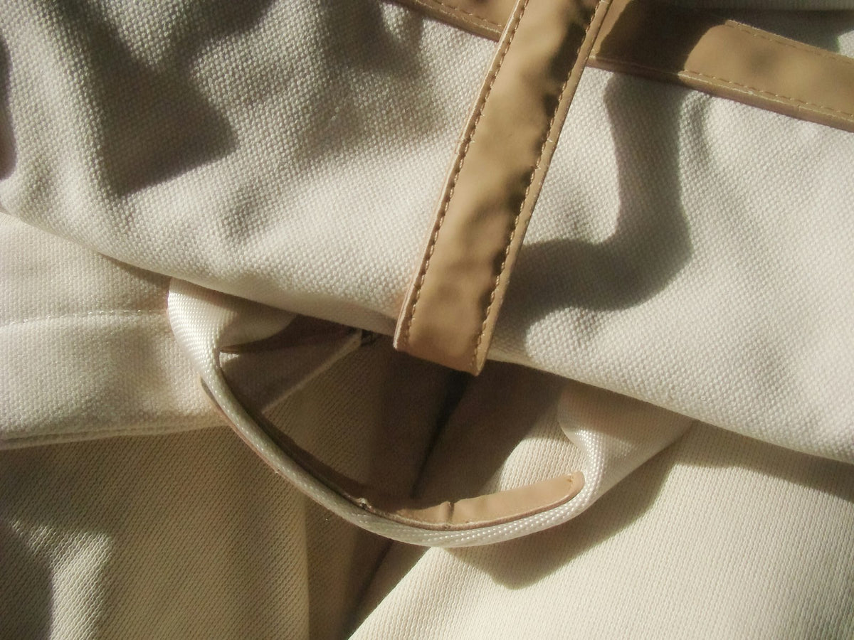 Détail de toile crème et de sangles en cuir naturel dans une lumière directe